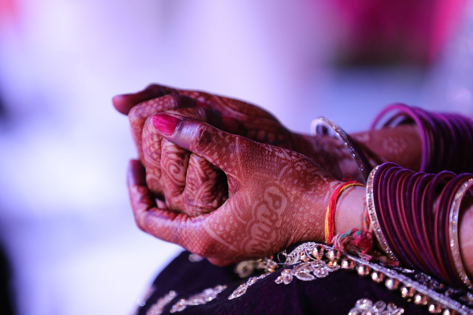 Hands decorated with mehndi, bangles and a neat festive nail finish